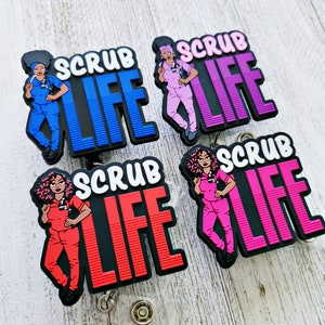 May include: Four colorful retractable badge holders with a cartoon illustration of a person wearing scrubs and the text "Scrub Life". The badge holders are black, blue, pink, and red.