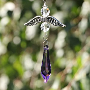 May include: A silver angel with crystal beads and a purple crystal teardrop hanging from it.