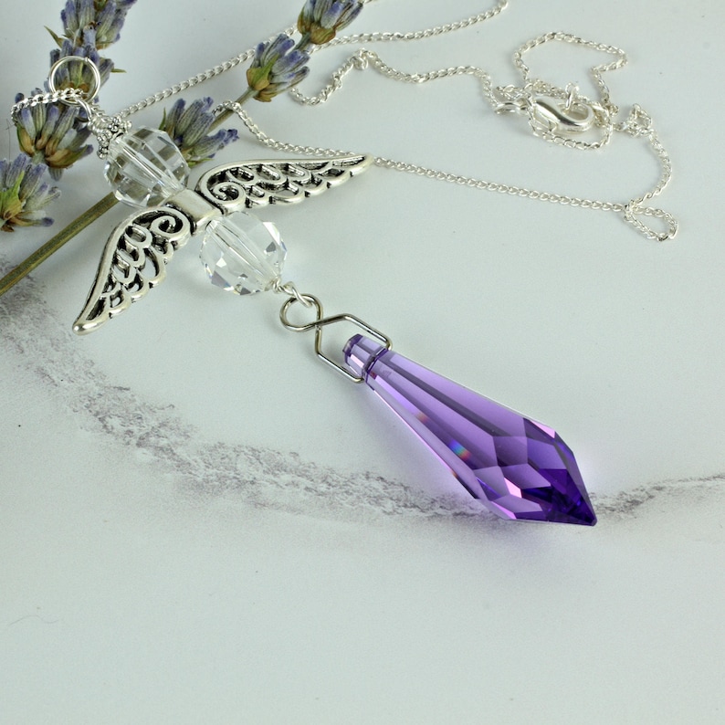 May include: A silver angel wing charm necklace with a clear crystal bead and a purple crystal pendant.