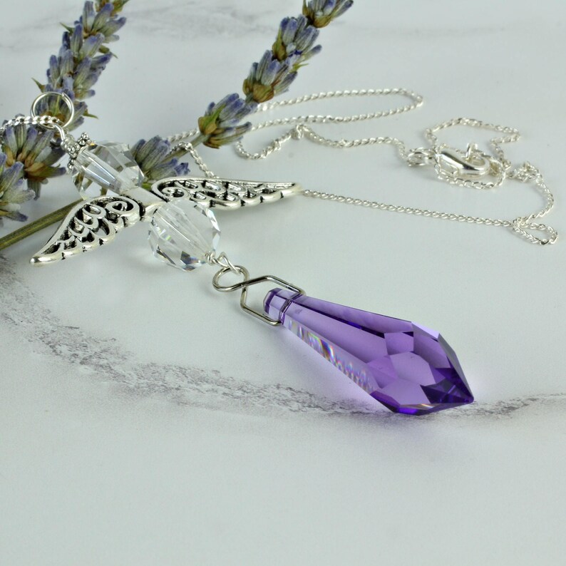 May include: A silver angel wing charm necklace with a clear crystal and a purple crystal pendant.