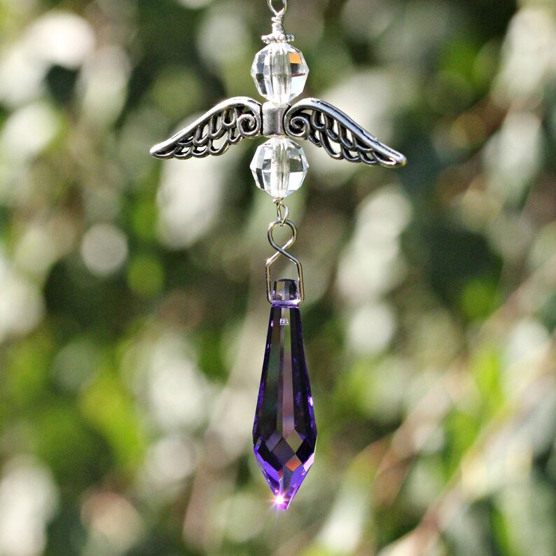May include: A silver angel with crystal beads and a purple crystal teardrop hanging from it.