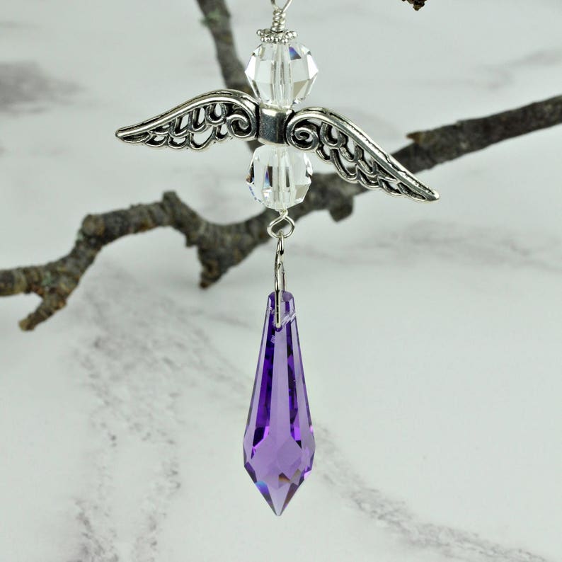 May include: A silver angel charm with crystal wings and a purple crystal teardrop pendant.