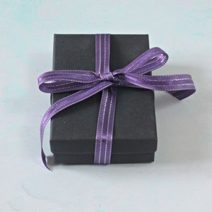 May include: A black gift box with a purple ribbon tied in a bow.