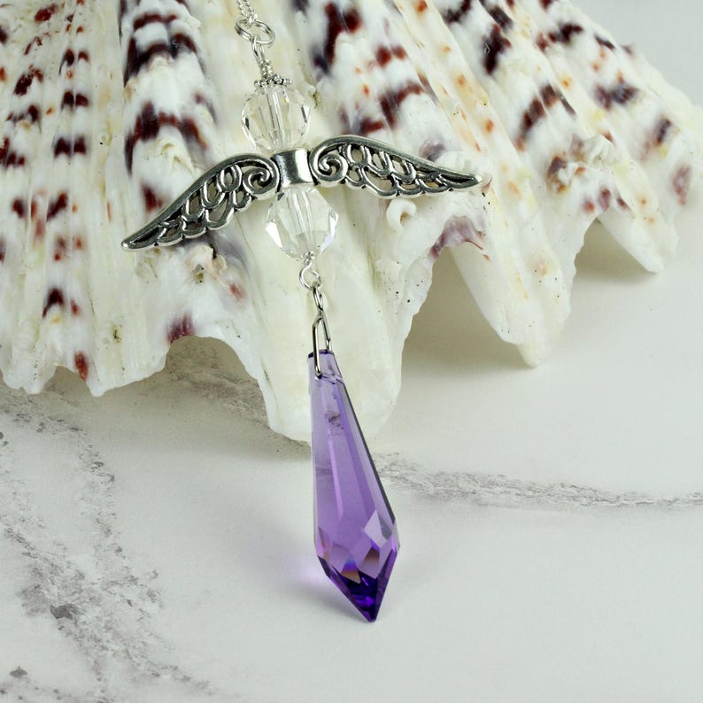 May include: A silver angel wing charm with clear crystal beads and a dangling purple crystal teardrop.