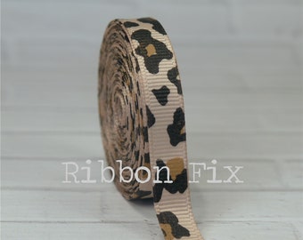Può includere: Un rotolo di nastro di grosgrain beige con stampa leopardata marrone e oro.