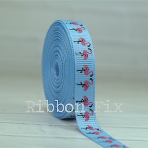 May include: A roll of light blue ribbon with a repeating pattern of pink flamingos. The ribbon is 1 inch wide and is perfect for adding a touch of tropical flair to your crafts.