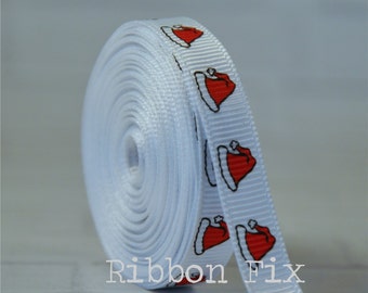 Könnte beinhalten: Weißes Satinband mit einem sich wiederholenden Muster aus roten Weihnachtsmützen. Das Band ist aufgerollt und der Text "Ribbon Fix" ist am unteren Rand des Bildes sichtbar.