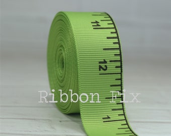May include: A roll of bright green ribbon printed with black ruler markings and numbers. The text "Ribbon Fix" is printed in white. The ribbon is a light green color.