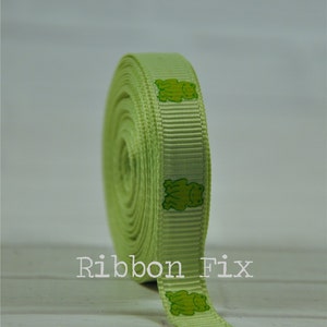 May include: A roll of light green ribbon with a repeating pattern of green frogs. The ribbon is 1 inch wide and is perfect for adding a touch of whimsy to crafts, gifts, and home decor.