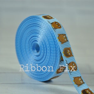 May include: A roll of light blue ribbon with a repeating pattern of brown owls. The ribbon is 1 inch wide and has a satin finish.