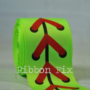 Può includere: Un rotolo di nastro verde lime con un motivo ripetuto di punti di cucitura da baseball rossi. Il nastro è etichettato "Ribbon Fix".