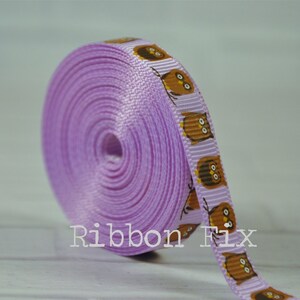 May include: A roll of lavender purple ribbon with a repeating pattern of brown owls. The ribbon is 1 inch wide.
