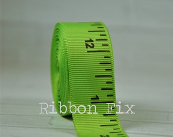 May include: A roll of bright green ribbon with black ruler markings. The ribbon is printed with inch measurements, with the number 12 visible. The text "Ribbon Fix" is printed on the ribbon.