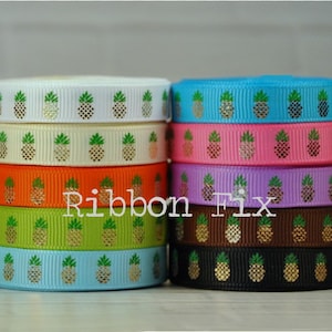 May include: A stack of ten different colored grosgrain ribbons with a gold pineapple print. The ribbons are in the colors white, cream, orange, green, light blue, turquoise, pink, purple, brown, and black.
