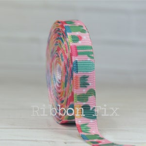 May include: A roll of pink ribbon with a repeating pattern of green cacti and colorful accents. The ribbon is tightly wound, showcasing the design. The text "Ribbon Fix" is visible on the ribbon.