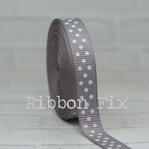 May include: A roll of gray grosgrain ribbon with white polka dots. The ribbon is 1 inch wide.