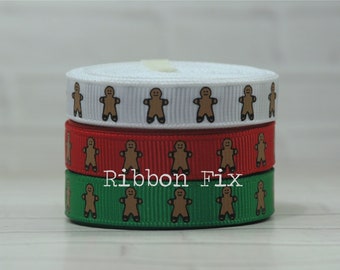 May include: Three rolls of ribbon with a gingerbread man pattern. The top roll is white, the middle roll is red, and the bottom roll is green.