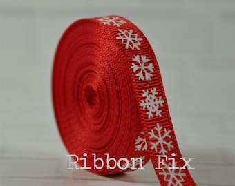 Könnte beinhalten: Rotes Band mit weißen Schneeflocken-Designs. Das Band ist aufgerollt und das Ende des Bandes liegt flach. Der Text "Ribbon Fix" ist auf das Band gedruckt.