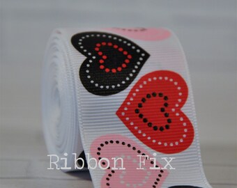 May include: White ribbon with a repeating pattern of black, red, and pink hearts with white polka dots. The hearts have a black outline and a white circle in the centre.