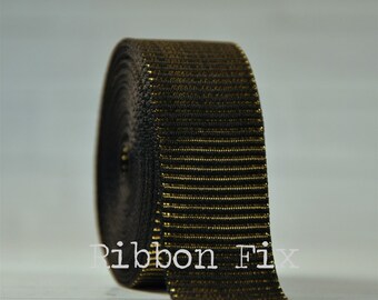 May include: A roll of black elastic ribbon with horizontal gold stripes. The ribbon is tightly wound, showcasing its texture and pattern. The text "Ribbon Fix" is visible on the ribbon.
