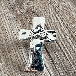 May include: A silver cross pendant with a fish design. The cross is textured and has a hammered finish.