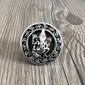 May include: Silver pendant featuring a detailed depiction of the Hindu deity Ganesha, surrounded by a circular border of Om symbols.