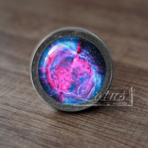 Może przedstawiać: Okrągły, srebrny gałka meblowa z wkładką szklaną przedstawiającą różowo-niebieską mgławicę.