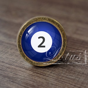 May include: A gold-toned knob with a blue glass insert featuring a white circle with the number "2" in black.
