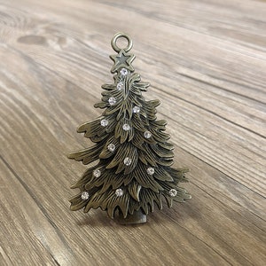 Op de afbeelding: Een gouden metalen kerstboomversiering met een ster bovenop en heldere strasssteentjes voor decoratie.