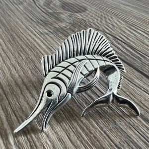 May include: A silver marlin fish pendant with detailed scales and fins. The pendant is a popular design for jewellery and accessories.