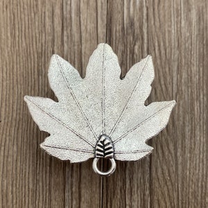 Pode incluir: Encanto de folha de bordo de metal prateado com um la&ccedil;o para prender a joias ou outras manualidades.