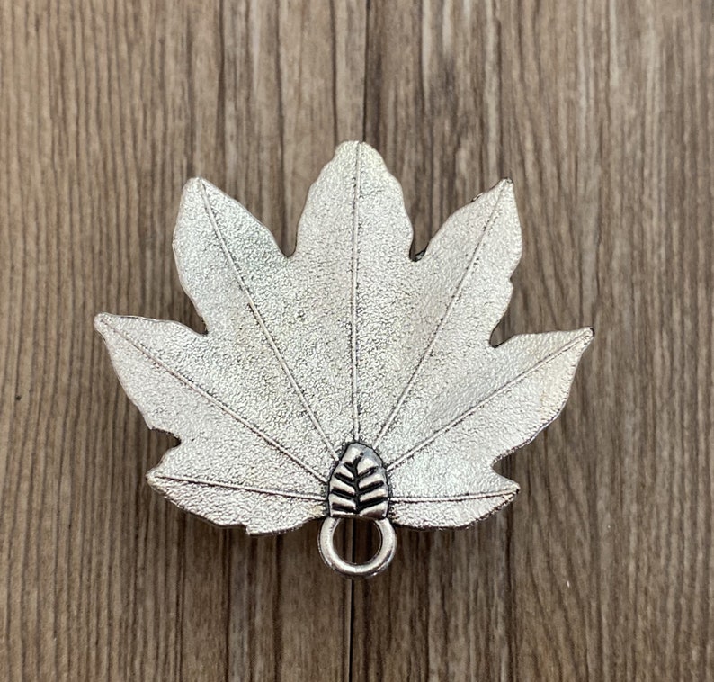 Pode incluir: Encanto de folha de bordo de metal prateado com um la&ccedil;o para prender a joias ou outras manualidades.
