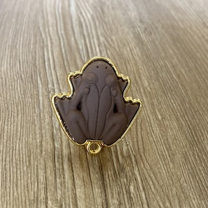 May include: A gold-coloured frog-shaped door knob with a brown frog design.