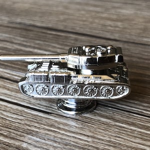 Może przedstawiać: Srebrna metalowa figurka czołgu o szczegółowym wzornictwie. Czołg ma długi lufę, wieżę i gąsienice. Figurka jest elementem dekoracyjnym.