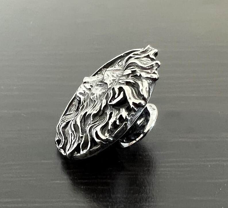 Peut inclure: Une bague en argent avec un motif de t&ecirc;te de lion d&eacute;taill&eacute;. La bague est de forme ovale et la t&ecirc;te de lion est tourn&eacute;e sur le c&ocirc;t&eacute;.