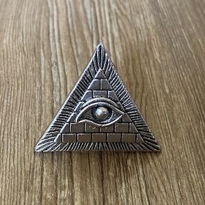 以下が含まれることがあります： 中央に目がついた銀色のピラミッド。ピラミッドはレンガ造りで、表面はテクスチャ加工されています。