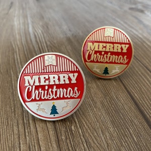 May include: Two red and gold round metal ornaments with the words "Merry Christmas" in white lettering. The ornaments feature a snowflake, a Christmas tree, and reindeer.