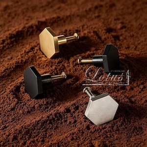 May include: Four hexagonal cabinet knobs in gold, black, and silver finishes. Each knob has a screw for installation. The knobs are displayed on a textured brown surface. The word "Lotus" is visible.