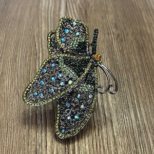 May include: A black metal butterfly hair clip with green and blue rhinestones.