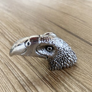 May include: A silver toucan-shaped door knob with a detailed design.