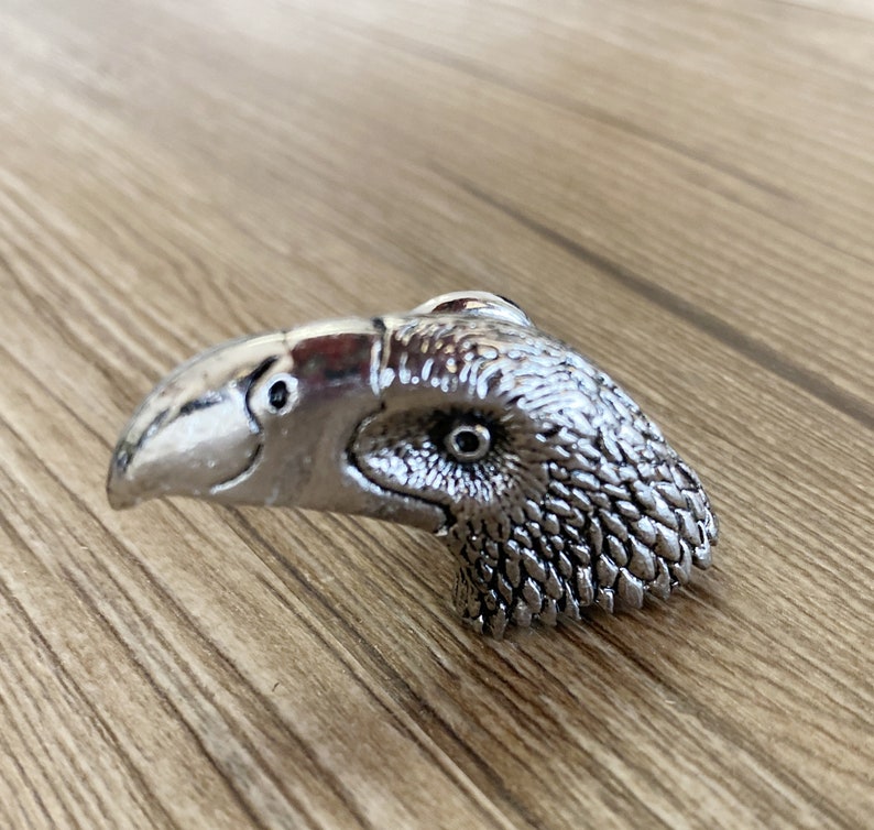 May include: A silver toucan-shaped door knob with a detailed design.