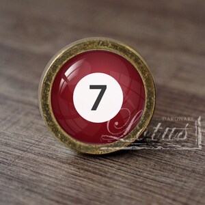 May include: A red and gold cabinet knob with a white circle and the number 7 in black.