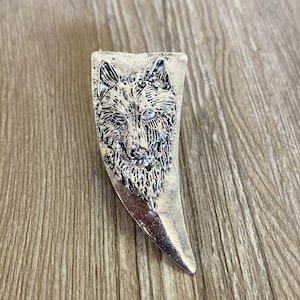 以下が含まれることがあります： 詳細なデザインが施された銀の狼の頭の形をしたリング。リングは狼の牙の形をしています。