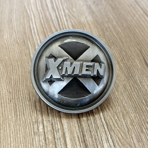 May include: A silver-toned metal belt buckle with the X-Men logo. The logo is a stylized X with the words "X-Men" written across it.