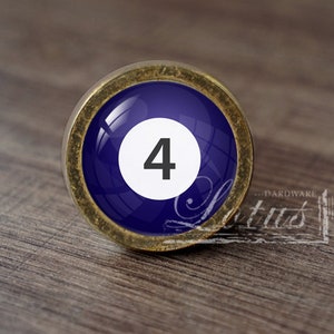 Puede incluir: Un pomo de armario redondo con una cara azul oscuro con el número 4 en blanco. El pomo tiene un borde de metal color latón. El texto "...DAREWARE lotus" es visible en el lado derecho.