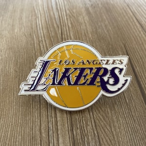 Könnte beinhalten: Ein silberner und weißer Los Angeles Lakers-Pin mit einem lila und gelben Basketball-Logo. Der Pin zeigt den Namen des Teams und die Stadt.