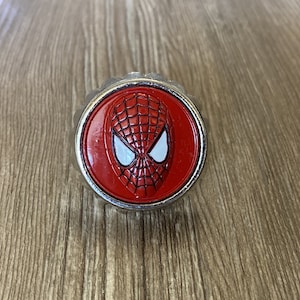 May include: A silver bottle opener featuring a red and black Spider-Man design.