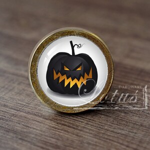 Pode incluir: Uma maçaneta de armário de Halloween preta e laranja com um design de abóbora.