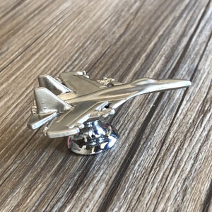 May include: Silver-toned metal fighter jet cabinet knob with a chrome base.