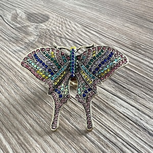 May include: A colourful butterfly ring with rhinestones in shades of pink, blue, green, and yellow.